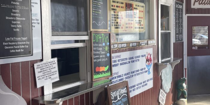 image00003 Ice cream window counter from outside view. Chalkboard menus with special flavors listed in colorful writing. Red siding on building. Small open windows with white trim.