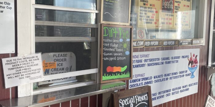 image00007 Ice cream window counter from outside view. Chalkboard menus with special flavors listed in colorful writing. Red siding on building.