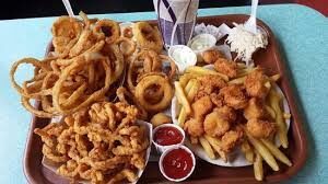images (3) Seafood platter menu items. Onion rings, clam strips, fried clams, french fries with ketchup served on a red tray