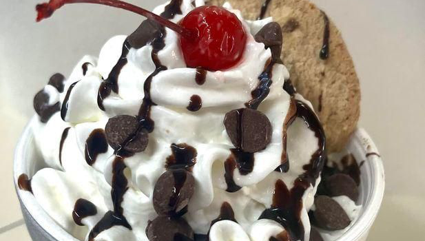 r0f1-dessert-Kool-Kone-2023-02-3 Ice cream sundae topped with whipped cream, chocolate sauce, hershey kisses, a cookie, and a cherry on top