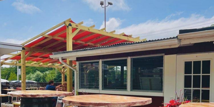 r20f-design-Kool-Kone Outdoor dining patio at Kool Kone with wooden tables on top of kegs, and wooden bar stools