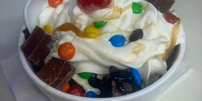 r790-dessert-Kool-Kone-2023-02-1 Ice cream sundae in bowl with whipped cream, caramel sauce, mini M&Ms, chocolate chunks, and a red cherry