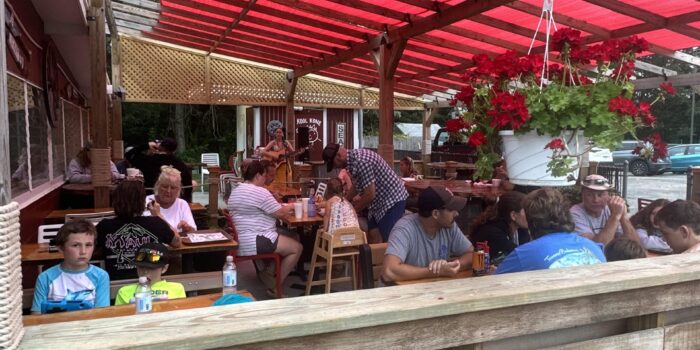 entertainment people enjoying their meals under a red canopy on the outdoor dining patio at Kool Kone